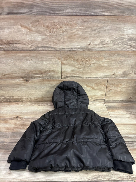 Back view of black Calvin Klein Jeans puffer jacket showcasing hood and ribbed cuffs on a wood floor