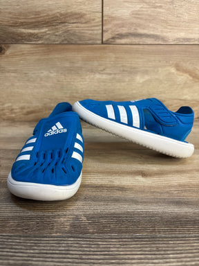 Blue kids' Adidas slip-on shoes with white stripes and soles on wood floor