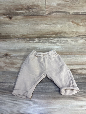 Flat lay of tan H&M drawstring joggers size 6M showing elastic waistband and rolled cuffs on wood background