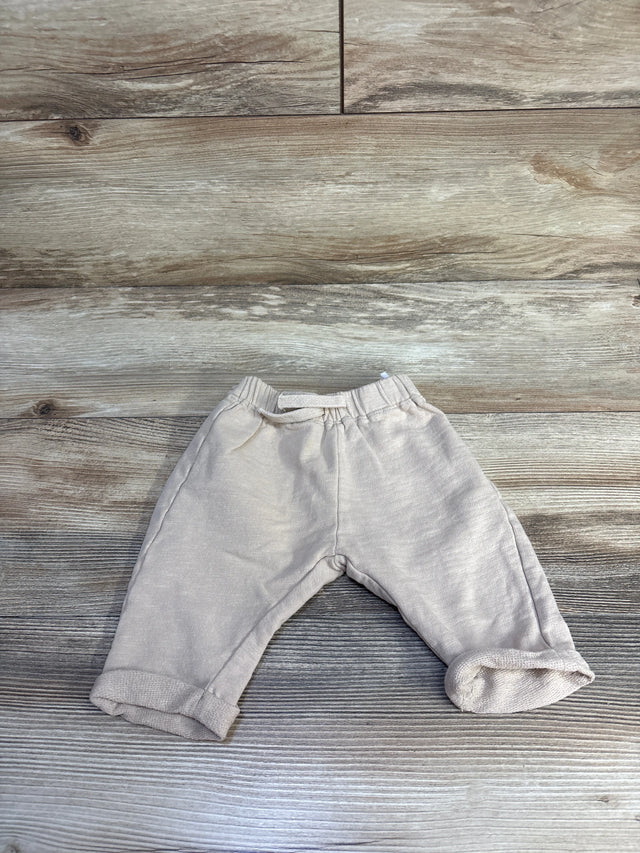 Flat lay of tan H&M drawstring joggers size 6M showing elastic waistband and rolled cuffs on wood background