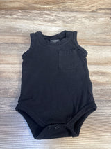 Black sleeveless baby bodysuit with chest pocket, snap closures, on wooden background