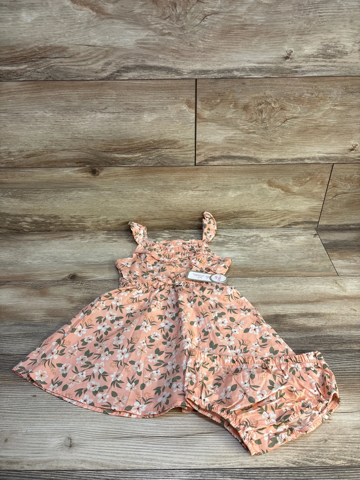 Pink floral baby dress and matching bloomers on wood background