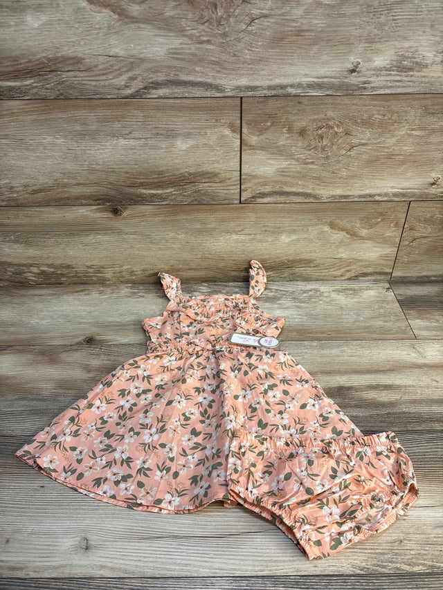 Pink floral baby dress and matching bloomers on wood background