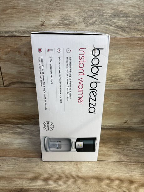 Front view of Baby Brezza Instant Baby Bottle Warmer box showing product image and 'instant warmer' branding on white box against wooden backdrop