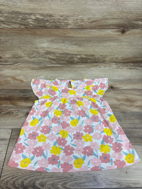 Front view of a pink and white floral dress with yellow flowers, flutter sleeves, and a gathered waist on a wood surface