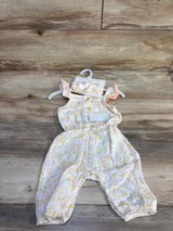 Flat-lay of newborn gauze jumpsuit with matching ruffle headband, pastel floral print, front buttons and leg snaps on wood