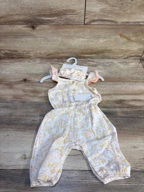 Flat-lay of newborn gauze jumpsuit with matching ruffle headband, pastel floral print, front buttons and leg snaps on wood