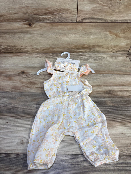 Flat-lay of newborn gauze jumpsuit with matching ruffle headband, pastel floral print, front buttons and leg snaps on wood