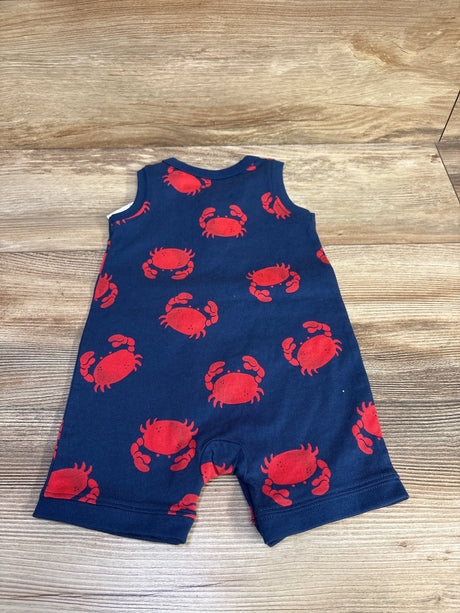 Flat lay of navy Henley shortie romper (6M) showing red crab print, sleeveless Henley front and snap crotch on wood background