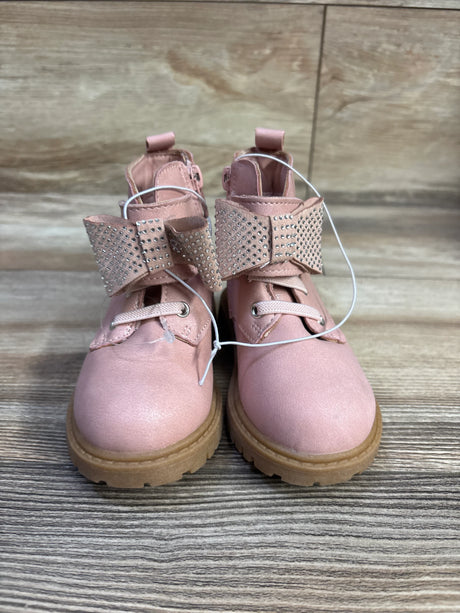 Front view of Daria bow ankle boots in pink showcasing rhinestone studded bows and tan lug soles on wood floor
