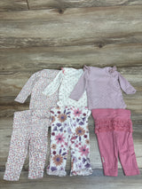 Top-down view of Huggies 6pc Bodysuit and Ruffle Pants Set showing six floral and dotted pieces on a wood floor