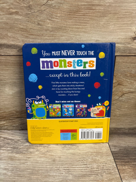 Back cover of Never Touch the Monsters board book showing colorful title, blurb text, monster illustrations, and wood tabletop background
