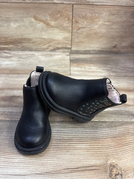 Angled view of Juicy Couture black ankle boots showcasing star-patterned side panels on a wood-look background