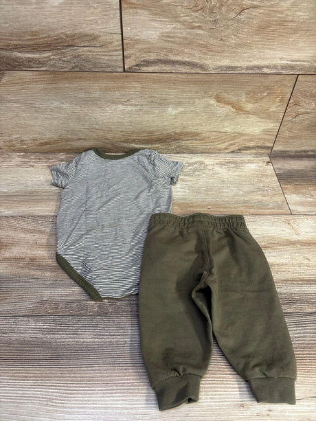 Nike 2pc baby set featuring a striped grey bodysuit and olive green joggers on a wood background.