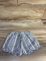 Top-down view of Baby Gap white and navy striped toddler shorts showcasing elastic pull-on waistband and scalloped ruffle hem on wood background