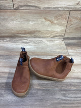 Front view of Cat & Jack brown toddler zipper ankle boots showing elastic side panel and blue pull tabs on wood floor