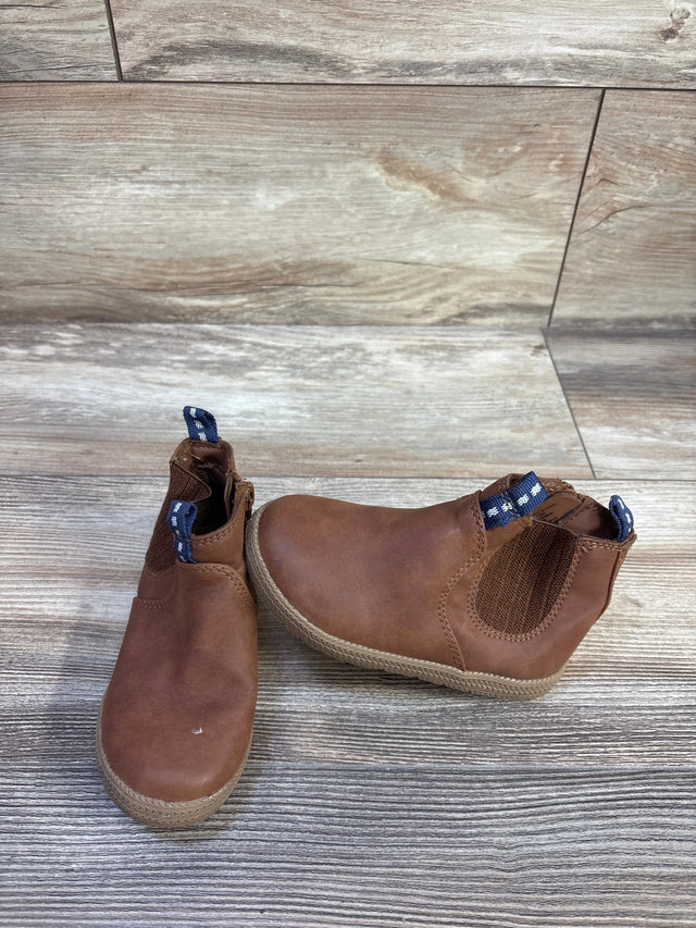 Front view of Cat & Jack brown toddler zipper ankle boots showing elastic side panel and blue pull tabs on wood floor