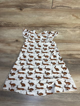 Flat lay of white baby dress with brown rabbit print and flutter sleeves on wood plank floor