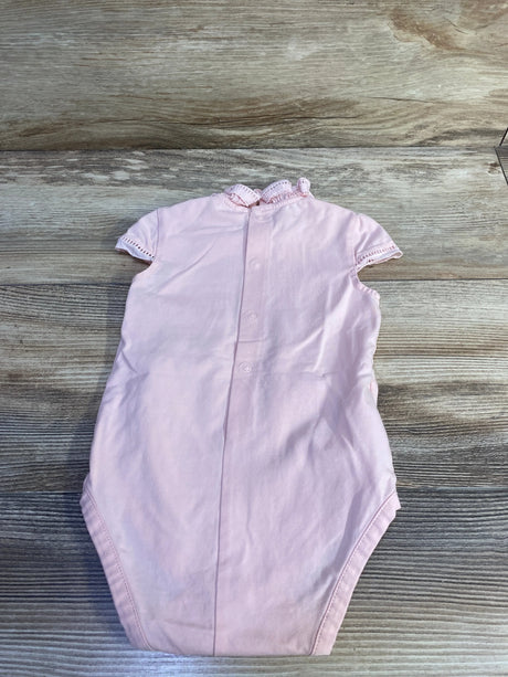 Top view of Mayoral pink ruffle-collar bodysuit showing back snaps and eyelet-trim sleeves on wood surface