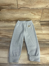 Flat lay of grey ribbed toddler pants showcasing elastic waistband and cuffed ankles on wood floor background