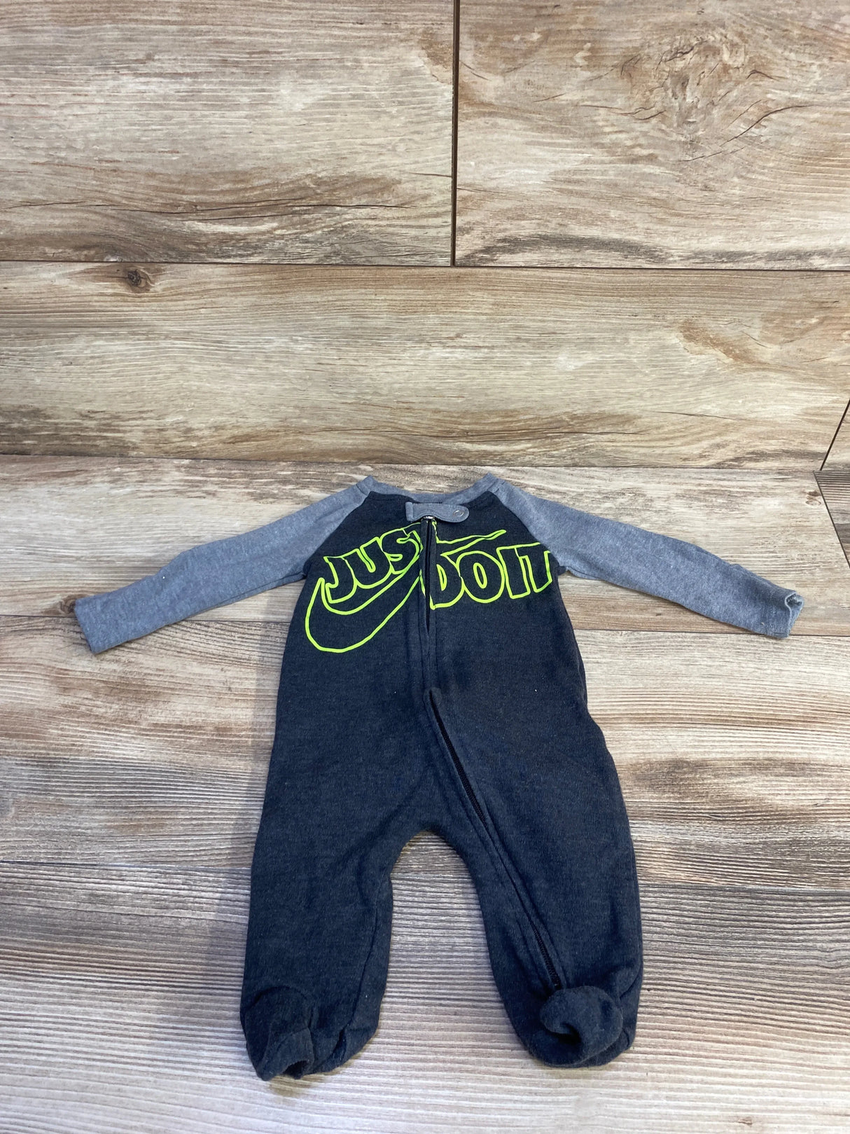 Flat lay of Nike sleeper, dark gray with lighter gray sleeves, neon yellow 'JUST DO IT' logo, front zipper, footed