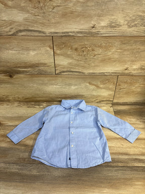 Light blue boys button-down shirt with long sleeves, laid flat on wood floor