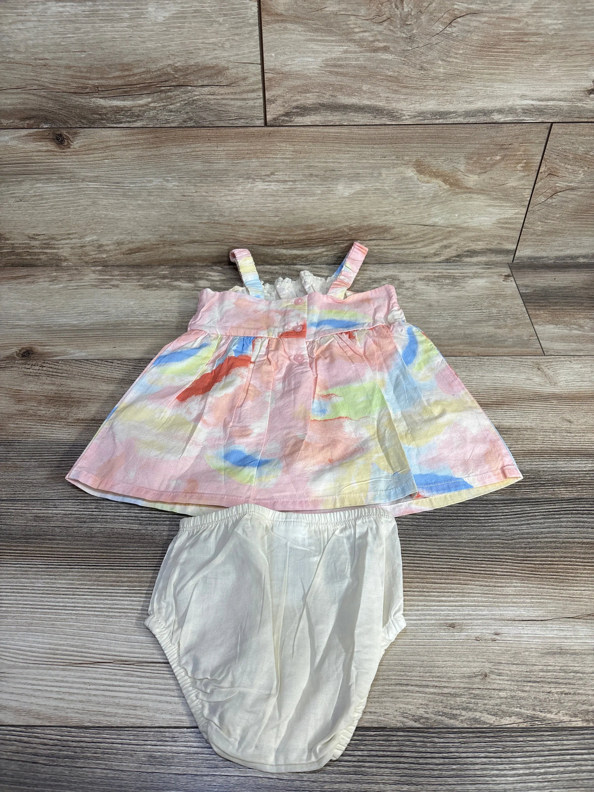 Top-down view of Carter's 2-piece multicolor dress with ruffle neckline and matching white bloomers on wood floor