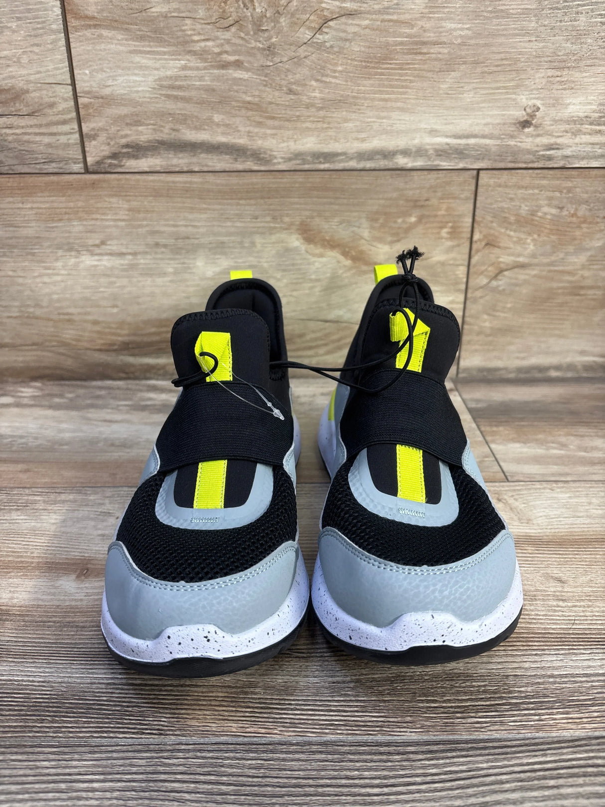 Front view of All in Motion Fern kids slip-on sneakers with grey mesh, neon yellow pull tabs and elastic strap on wood floor