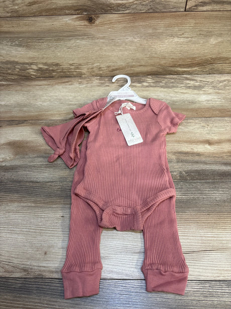 Pink ribbed baby romper and matching pants set on hanger, wooden background