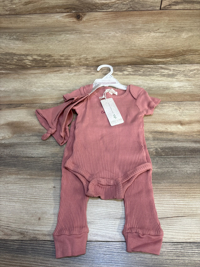Pink ribbed baby romper and matching pants set on hanger, wooden background