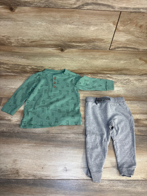 Long sleeve green infant shirt with animal print and gray baby pants on wood floor