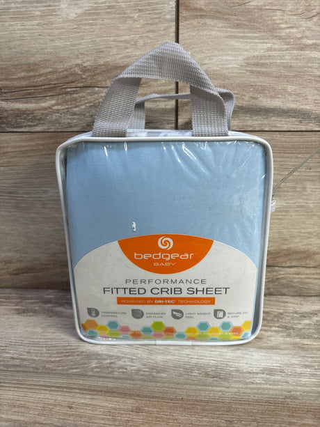 Front of packaged Bedgear Baby Dri-Tec fitted crib sheet in light blue with label and handle on wood background