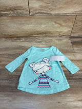 Mint green long sleeve toddler shirt with girl cartoon graphic, laid on wood floor