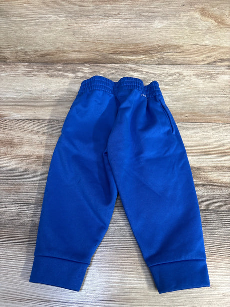 Front view of blue Nike Therma-Fit joggers showcasing elastic waistband, tapered legs, and cuffed ankles on a wood-grain background