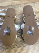 Janie & Jack toddler flower sandals, bottom view showing clean brown ribbed soles and size stickers on wood background