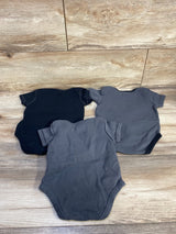 Top-down view of 3-pack baby bodysuits showcasing short sleeves and crew necks in dark grey and black on wood background