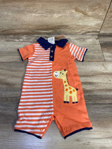 Front flat lay of orange baby polo romper with navy collar, striped left panel and giraffe patch, snap leg closures on wood