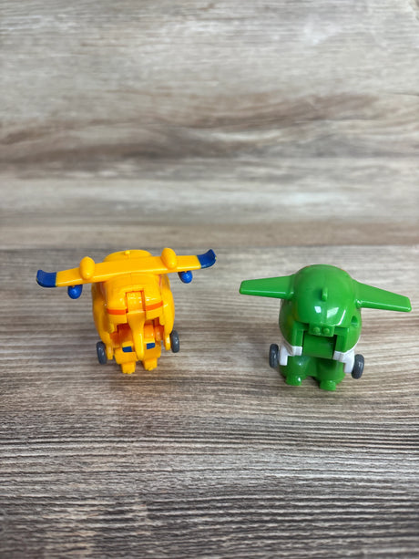 Two small toy planes on wooden surface, one yellow with blue accents, one green with white details