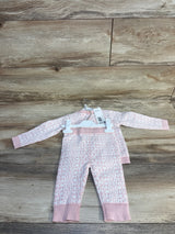 Pink baby onesie with white letter print, long sleeves, on hanger over wood floor