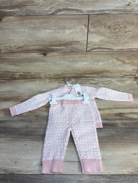 Pink baby onesie with white letter print, long sleeves, on hanger over wood floor
