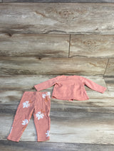 Flat lay of Carter’s 2pc pink button-top and floral leggings set, back of top and leggings on wood background