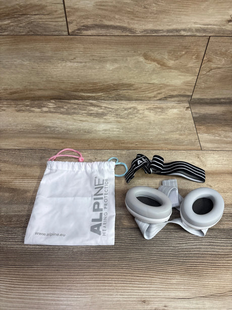 Top view of Alpine Muffy Baby noise cancelling ear muffs in white with storage pouch and headband on a wood floor