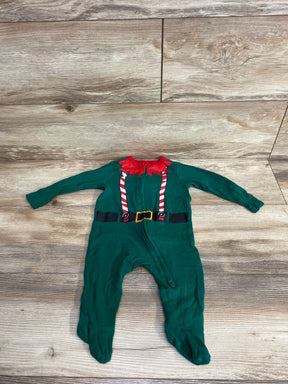 Green baby elf costume with red collar, candy cane suspenders, and black belt on wood floor