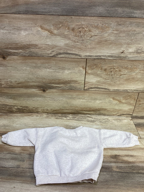 Top view of Nike ivory pullover sweatshirt with long sleeves and ribbed cuffs on a wood plank background