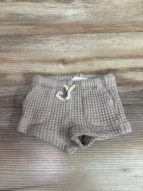 Top view of H and M beige knit drawstring shorts showcasing front pockets with a wood grain background