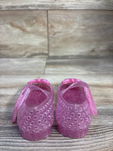 Rear view of pink glitter jelly Mary Jane flats, size 5C, showing heart cutouts and butterfly strap on wood background
