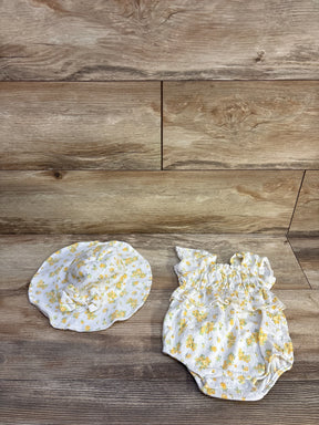 Top-down view of white 0-3M floral smocked bubble romper and matching sun hat showcasing ruffled smocking, snap crotch and yellow flower print on wood background