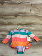 Top-down view of girls' one-piece rashguard swimsuit by Eddie Bauer with wide colorful stripes and front zipper on wood floor