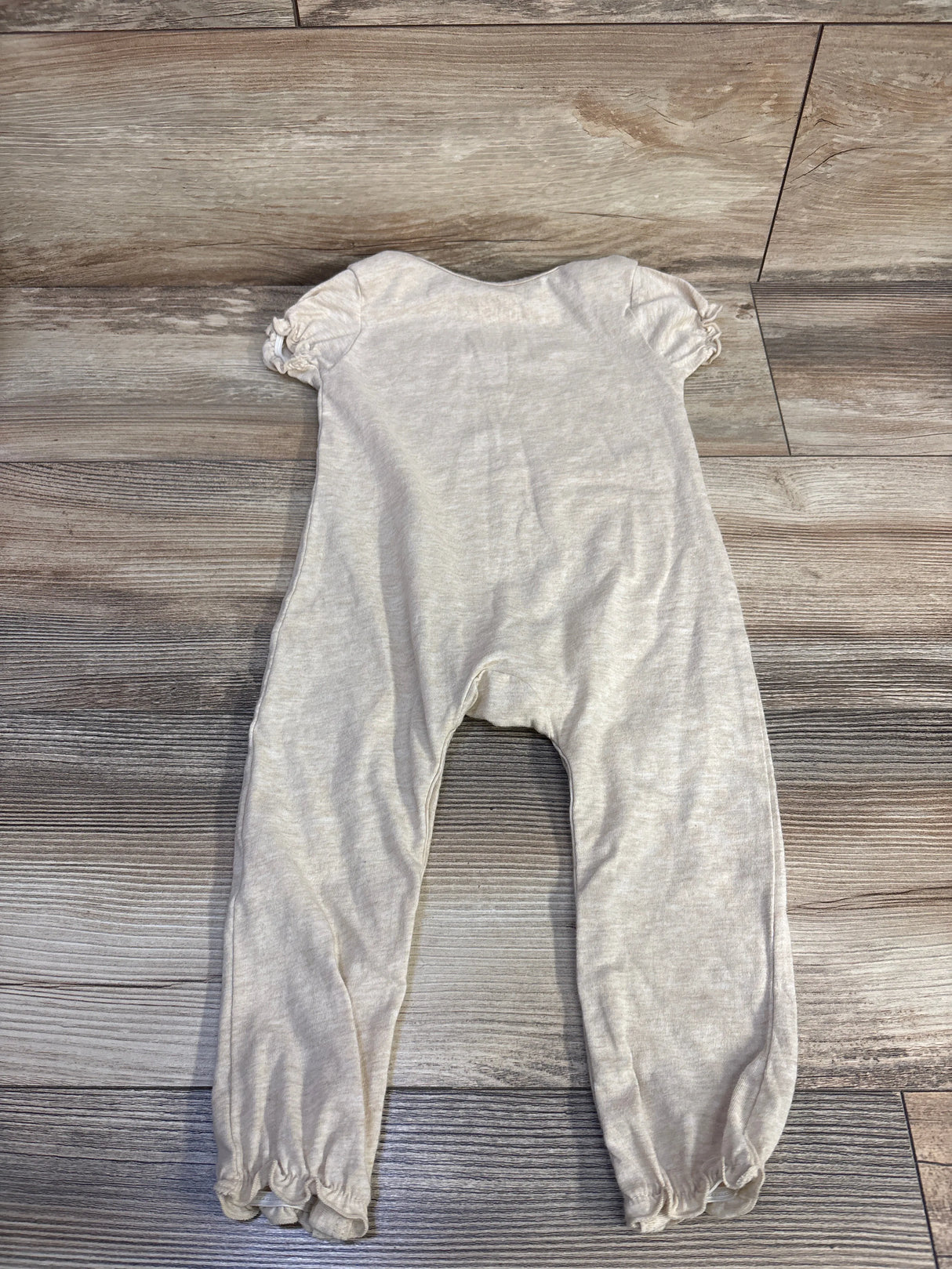 Back flat lay of beige Disney Baby Winnie the Pooh jumpsuit (18 months) showing puff sleeves and elasticized ankles on wood floor background