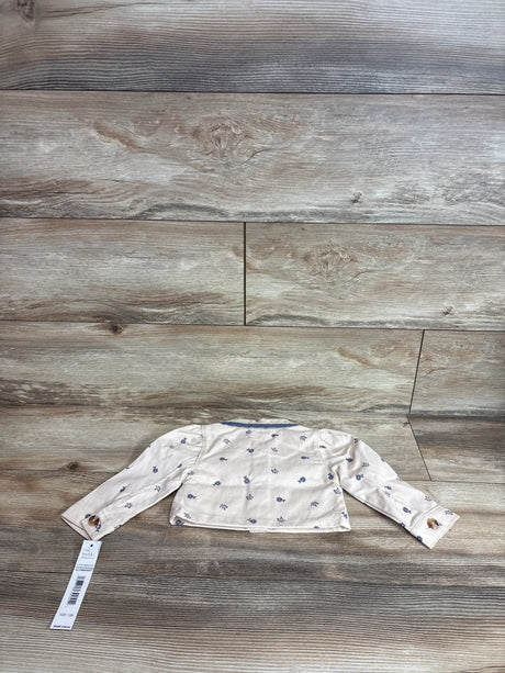 Back view of Nicole Miller beige button-up denim jacket showcasing blue floral print and button cuffs on wood background